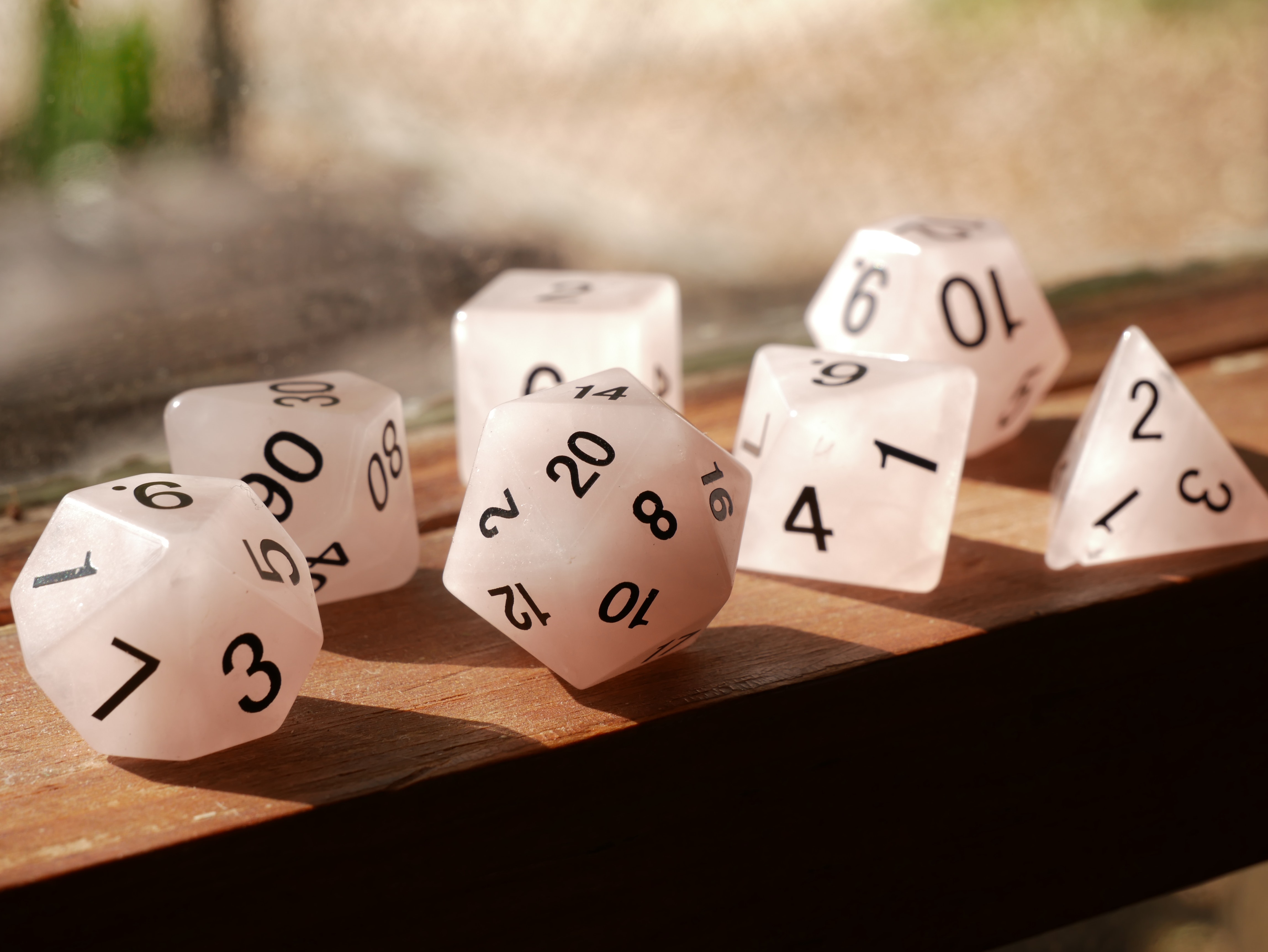 a set of clear polyhedral dice resting on a wooden windowsill